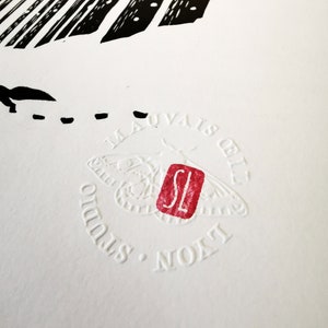 May include: Close-up of a white print with black and red accents. The print features a moth design, the text "MAUVAIS &OElig;IL STUDIO LYON", and a red stamp with the letters "SL".