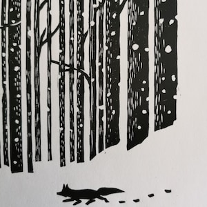 May include: Black and white linocut print of a winter forest scene. Tall, vertical trees dominate the background, with a fox silhouette walking in the snow. The print has a minimalist style and a textured appearance.