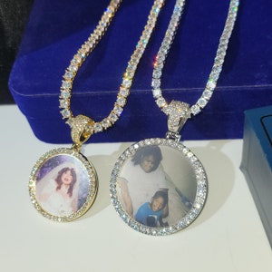May include: Two silver and gold chains with round photo pendants. The pendants are set with clear cubic zirconia stones and feature a photo of a woman and a child.