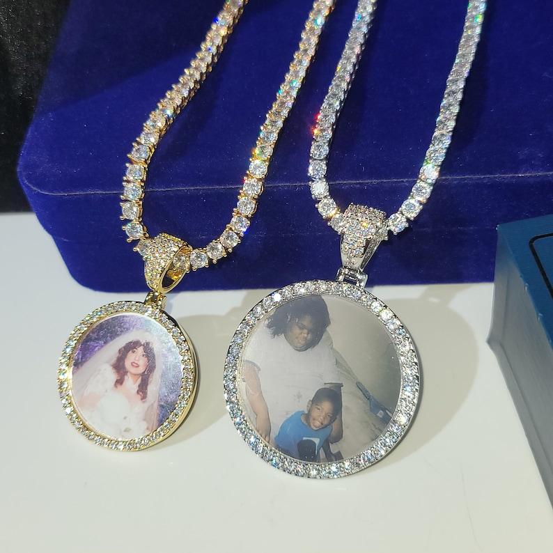 May include: Two silver and gold chains with round photo pendants. The pendants are set with clear cubic zirconia stones and feature a photo of a woman and a child.