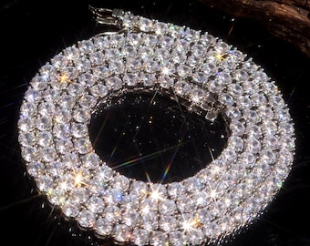 May include: A dazzling silver necklace, densely packed with numerous clear, round gemstones. The necklace is arranged in a circular pattern, with a secure clasp visible at the top. The gemstones reflect light, creating a brilliant display.