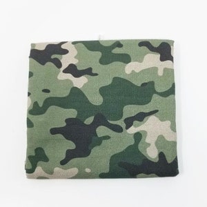 May include: A green, brown, and black camouflage fabric with a textured surface.
