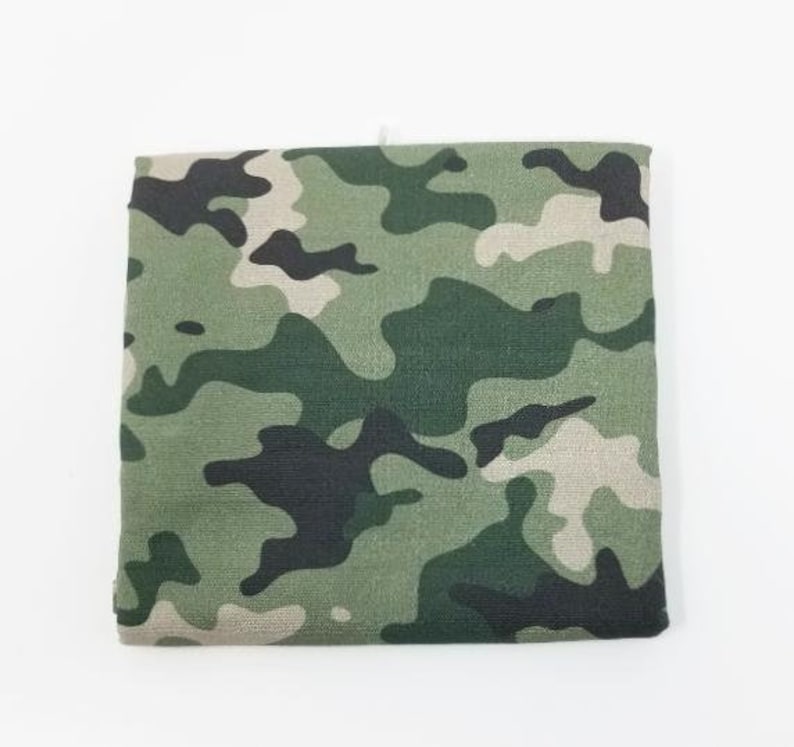 May include: A green, brown, and black camouflage fabric with a textured surface.