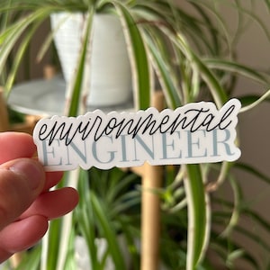 May include: White sticker with black text that reads "environmental engineer" in a cursive font. The sticker has a light blue background.