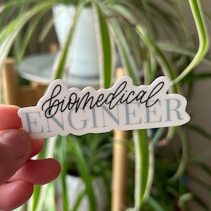 May include: A white sticker with the text "biomedical engineer" in black cursive lettering. The sticker has a light blue background.