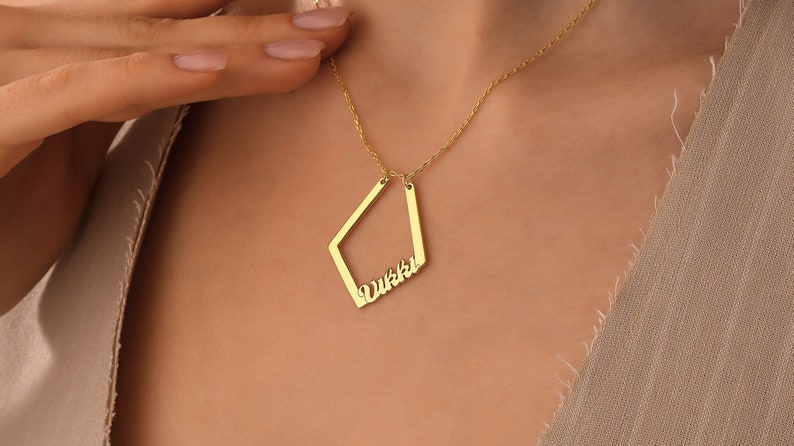 May include: A gold necklace with a diamond-shaped pendant that says "Vikki" in cursive.