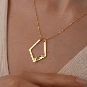May include: Gold necklace with a geometric pendant featuring the name "Vikki" in a cursive font.