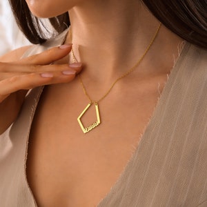 May include: A gold necklace with a diamond-shaped pendant that says "Dushka" in cursive.