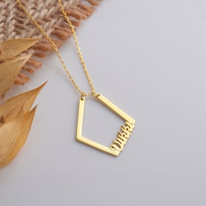 May include: Gold necklace with a geometric pendant featuring the name "Wikki" in a cursive font.