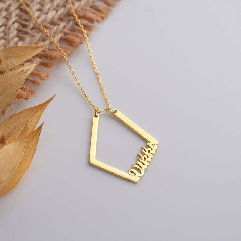 May include: Gold necklace with a geometric pendant featuring the name "Wikki" in a cursive font.