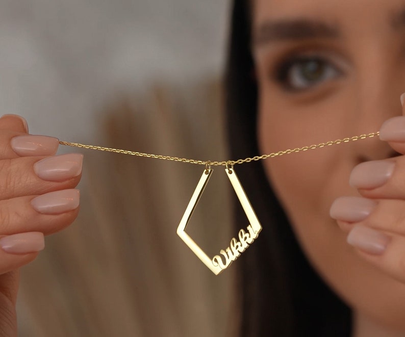May include: A gold necklace with a diamond-shaped pendant featuring the name "Vikki" in cursive script.