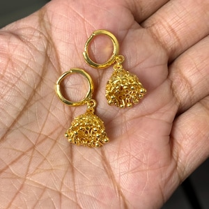 May include: A pair of gold hoop earrings with small, dangling bells. The bells are made of tiny gold beads.