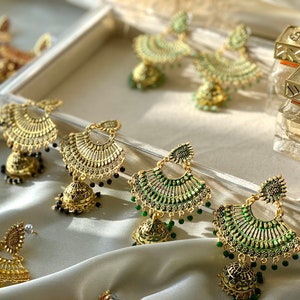 May include: A set of six pairs of gold and green dangle earrings with intricate designs. The earrings feature a bell-shaped charm and are adorned with small beads.