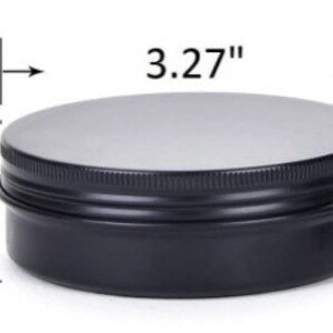 May include: A black metal tin with a silver lid. The tin measures 3.27 inches in diameter and 1.10 inches in height. The lid is flat and the sides of the tin are ridged.