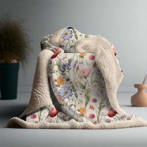 May include: A soft, plush throw blanket with a floral pattern featuring a variety of colorful flowers, including pink, red, blue, and yellow. The blanket is made of a soft, fluffy material and is perfect for cuddling up on the couch.