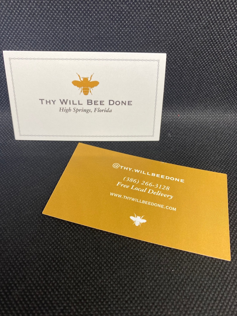 May include: Two business cards with a bee logo. One card is white with the text "THY WILL BEE DONE" and "High Springs, Florida." The other card is gold with contact information and a bee logo.