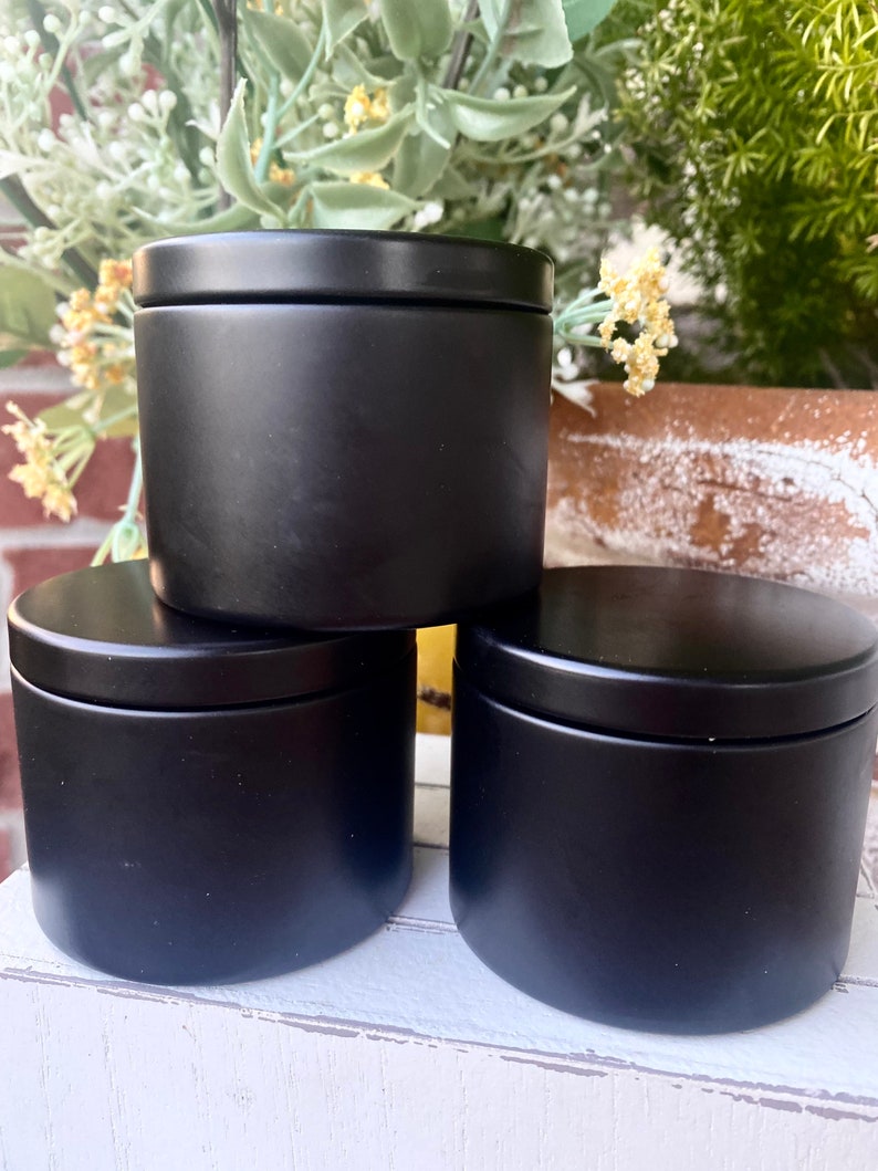 Pu&ograve; includere: Tre contenitori cilindrici con finitura nera opaca e coperchi abbinati. I contenitori sono disposti in una pila con uno posizionato sopra gli altri due, caratterizzati da un esterno liscio a tinta unita e un design semplice e uniforme.
