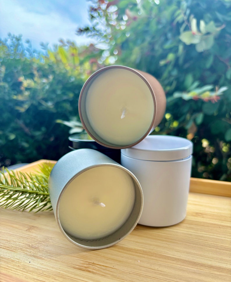 May include: Three cylindrical candles in metal tins, one silver, one white, and one copper-toned, each filled with smooth off-white wax and featuring a single centered cotton wick. The candles are arranged in a cluster, showcasing their metallic finishes.
