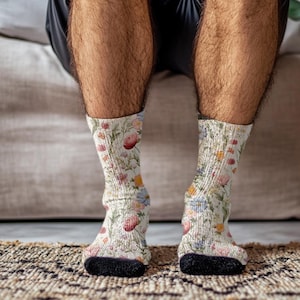 May include: Crew socks with a floral design. The socks have a cream background with a pattern of colourful flowers, including red, pink, yellow, and blue blooms. The heels and toes are black.