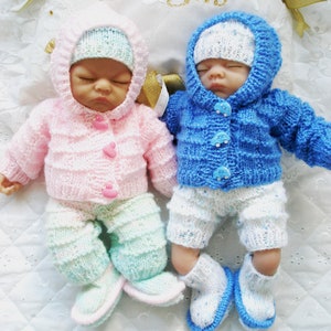 Puede incluir: Dos conjuntos de muñeca de punto, uno en rosa y verde y otro en azul y blanco. Ambos conjuntos incluyen un gorro, un suéter, pantalones y botines.