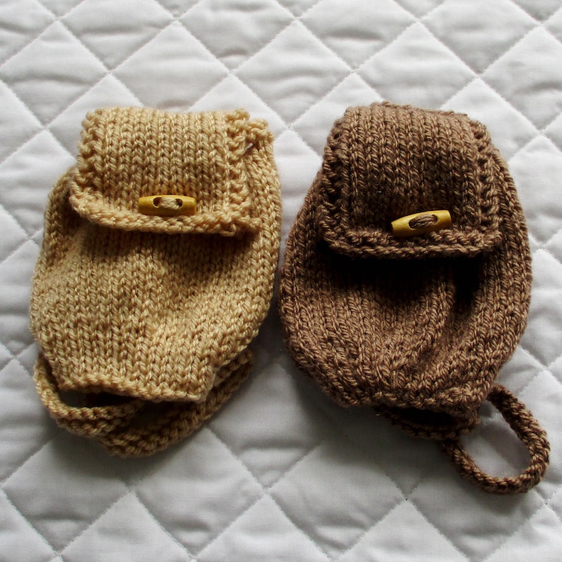 May include: Two small knitted bags with a flap and a button closure. One bag is beige and the other is brown.