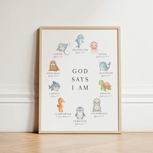 May include: A framed wall art print featuring watercolor illustrations of sea creatures arranged in a circle around the text GOD SAYS I AM. Each animal is paired with a word and scripture reference, including a stingray, dolphin, jellyfish, narwhal, turtle, seal, penguin, seahorse, shark, and walrus.