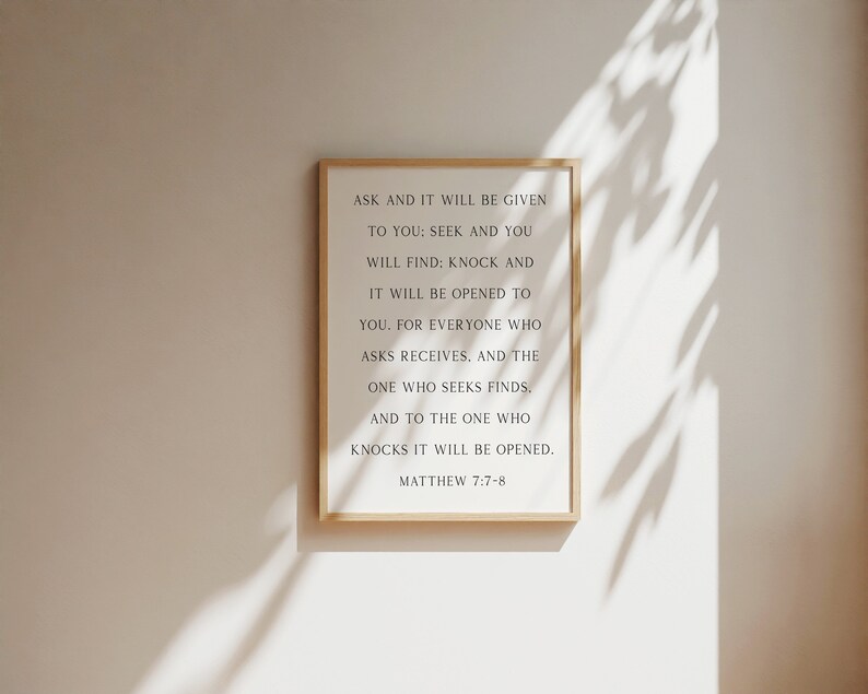 K&ouml;nnte beinhalten: Ein rechteckiges Wandbild in einem hellen Holzrahmen mit schwarzem Text auf wei&szlig;em Hintergrund, der lautet: ASK AND IT WILL BE GIVEN TO YOU: SEEK AND YOU WILL FIND: KNOCK AND IT WILL BE OPENED TO YOU. FOR EVERYONE WHO ASKS RECEIVES, AND THE ONE WHO SEEKS FINDS, AND TO THE ONE WHO KNOCKS IT WILL BE OPENED. MATTHEW 7:7-8.
