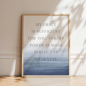 May include: A framed wall art print featuring the text MY GRACE IS SUFFICIENT FOR YOU, FOR MY POWER IS MADE PERFECT IN WEAKNESS. 2 CORINTHIANS 12:9 in black serif font. The background has a white top that fades into a blue watercolor gradient.