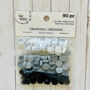 May include: A package of 90 piece white, gray, and black hexagonal beads. The package is labeled "bead landing" and "CREATIONS | CRÉATIONS BEADS | PERLES". The beads are made of zinc alloy and are nickel free.