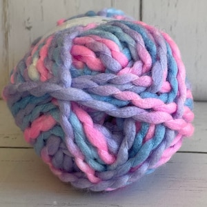 May include: A ball of yarn in a light blue, pink, and purple color combination. The yarn is thick and fluffy, and it is perfect for knitting or crocheting.