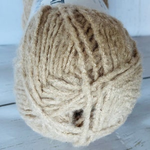 May include: A ball of beige yarn with a fuzzy texture.