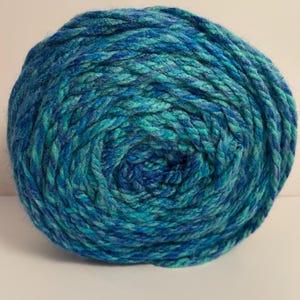 May include: A ball of yarn in shades of blue and teal. The yarn is tightly wound, creating a textured surface. This yarn is suitable for knitting or crocheting projects.