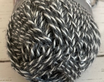 May include: A skein of black and white yarn. The yarn is a blend of wool and acrylic.