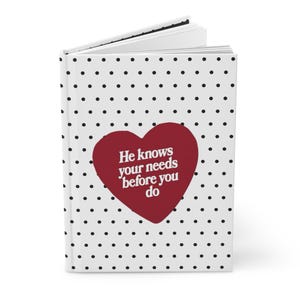 Puede incluir: Un diario blanco con un patrón de lunares negros y el texto "He knows your needs before you do" dentro de un corazón burdeos. El diario está abierto, revelando las páginas en blanco.