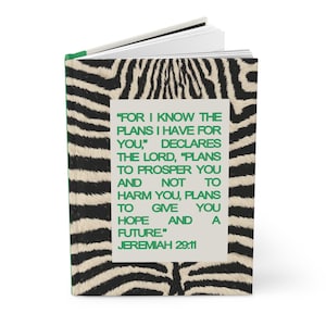May include: A hardcover journal with a zebra print cover. The journal features a quote from Jeremiah 29:11 in a green frame. The pages are white, and the spine is green.