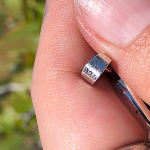 May include: Close-up of a silver ring with the number "925" engraved on the side.