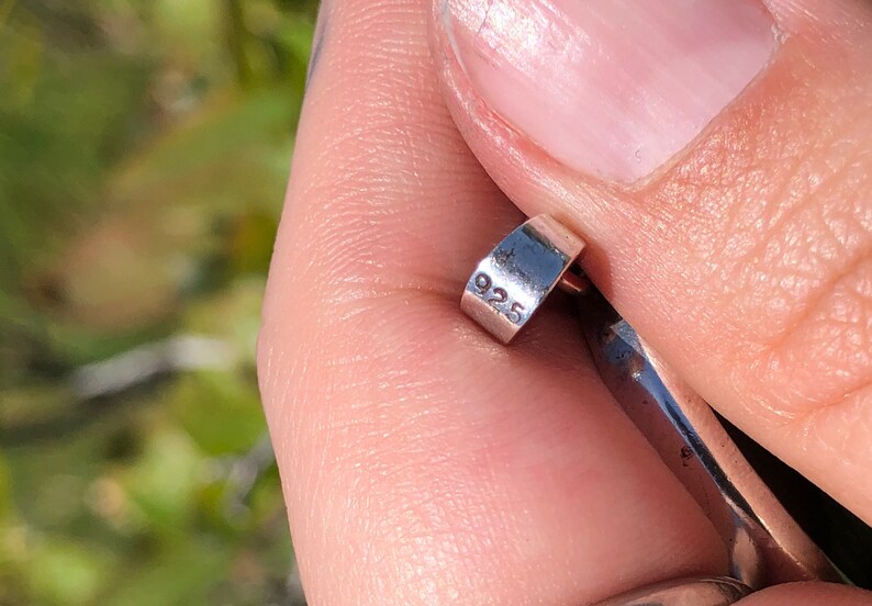May include: Close-up of a silver ring with the number "925" engraved on the side.