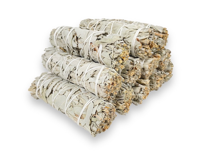 May include: A bundle of white sage smudge sticks tied with twine. The sticks are arranged in a pyramid shape.