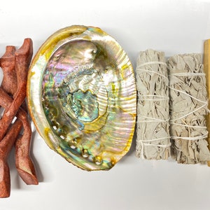 May include: A set of smudging tools including a wooden stand, a white sage smudge stick, a palo santo stick, and an abalone shell.