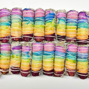 May include: A set of 20 white sage smudge sticks wrapped with colorful rose petals. The petals are arranged in a rainbow pattern, with each stick featuring a different color combination.