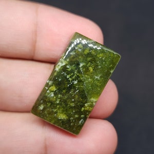 May include: A green and white rectangular cabochon gemstone with a mottled pattern.