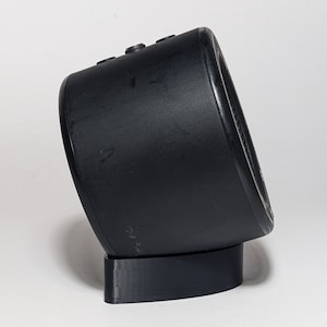 May include: A black cylindrical speaker with a rounded top and a base. The speaker has a smooth, matte finish.