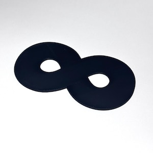 Peut inclure: Un objet noir en forme de huit, avec deux extrémités circulaires reliées par un pont étroit. Chaque cercle a un trou circulaire plus petit au centre. L'objet est posé sur un fond blanc.