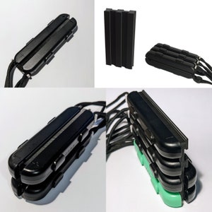 May include: A set of four black plastic cases with a green accent. The cases are stacked on top of each other and have a lanyard attached.