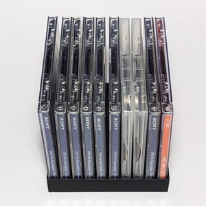 Könnte beinhalten: Ein Stapel von 12 DVD-RW-Discs, 11 sind von der Marke Sony und 1 von der Marke TDK. Die Discs befinden sich in einem durchsichtigen Kunststoffgehäuse und sind mit dem Markennamen und dem Disc-Typ beschriftet.