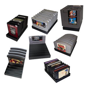 May include: A collection of retro video game cartridges, including Nintendo, Super Nintendo, and Sega Genesis games. The cartridges are displayed in black display stands. Some cartridges have colourful labels.