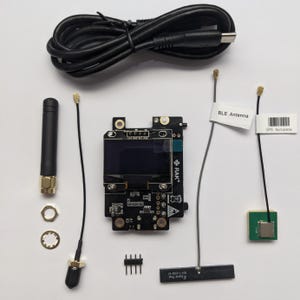 Könnte beinhalten: Eine schwarze Platine mit einem kleinen Bildschirm, einer schwarzen Antenne und verschiedenen anderen Komponenten. Die Platine ist mit "RAK" beschriftet. Das Bild zeigt auch ein schwarzes USB-Kabel, eine kleine grüne Platine und drei goldfarbene Steckverbinder.