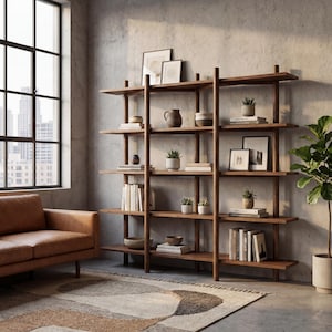May include: A dark wood bookcase with multiple shelves, displaying books, small plants, and decorative items. The bookcase is against a concrete wall, with a leather sofa and a patterned rug in the foreground. A large window offers a view of a cityscape.