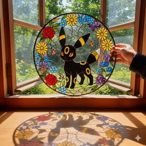 Może przedstawiać: Okrągły witraż przedstawiający czarną postać Umbreona, otoczoną kolorowymi kwiatami i motylami. Projekt zawiera czerwone róże, żółte stokrotki oraz niebieskie i fioletowe kwiaty. Okno wisi przed oknem.