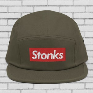 May include: A green 5-panel cap with a red box and white text that says "Stonks".